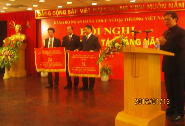 Đồng chí Đặng Hùng Minh, Ủy viên Thường vụ, Chủ nhiệm Ủy ban kiểm tra Đảng ủy Khối trao cờ của Đảng ủy Khối Doanh nghiệp Trung ương cho các tổ chức Đảng của Ngân hàng Ngoại thương Việt Nam