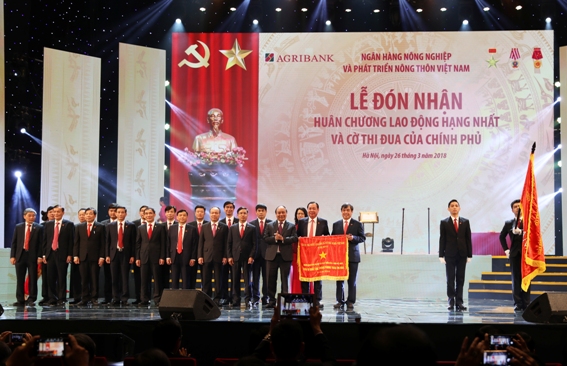 Thay mặt Đảng và Nhà nước, Thủ tướng Chính phủ Nguyễn Xuân Phúc gắn Huân chương Lao động hạng Nhất lên lá cờ truyền thống và trao Cờ thi đua của Chính phủ cho Agribank