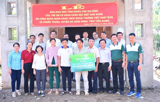 Đại diện lãnh đạo Công đoàn Vietcombank trao tượng trưng biển tài trợ số tiền 50 triệu đồng cho gia đình ông Huỳnh Văn Được