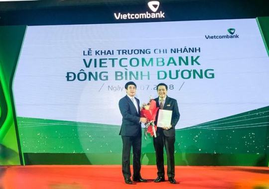 Chủ tịch HĐQT Vietcombank  Nghiêm Xuân Thành trao Quyết định và tặng hoa chúc mừng Giám đốc Vietcombank Đông Bình Dương Nguyễn Khánh Thắng