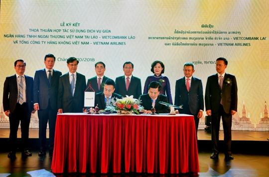 Vietcombank Lào (bên trái) và ông Ngô Sỹ Anh – Trưởng Chi nhánh Vietnam Airlines Lào ký kết thỏa thuận cung cấp dịch vụ trước sự chứng kiến của Lãnh đạo cấp cao 2 nước Việt Nam, Lào và Vietcombank