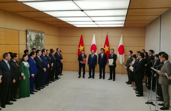 Nghiêm Xuân Thành - Chủ tịch HĐQT Vietcombank (bên trái) và ông Kazuhiko Amakawa - Tổng Giám đốc điều hành JBIC (bên phải) thực hiện nghi thức trang trọng tại Lễ trao văn kiện trước sự chứng kiến của Thủ tướng Chính phủ Nước CHXHCN Việt Nam Nguyễn Xuân Phúc và Thủ tướng Nhật Bản Shinzo Abe